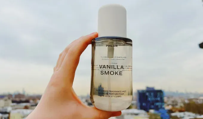 phlur-fragrance-review: A hand holds a gray body mist up against the NYC skyline. Original photo.' title='I Tried All 22 Phlur Fragrances and Here’s How I’m Ranking Them (with Original Photos)