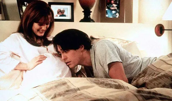 Movies About Pregnancy - A pregnant Julianne Moore sits in a white gown in a bed while co-star Hugh Grant leans over to listen to her belly.' fetchpriority='auto' title='25 Movies About Pregnancy That Will Make You Laugh Cry and Give You All the Feels (And Not Because of Hormones)
