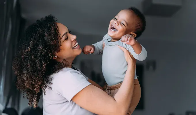 realistic-daily-schedules-for-kids: a mom holding a baby' fetchpriority='auto' title='5 Realistic Daily Schedules for Kids From Ages 0 to 11 According to Experts