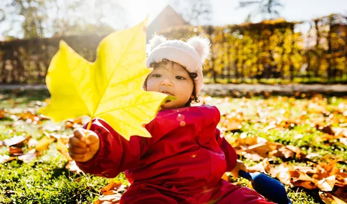 a baby girl sitting on the grass playing with autumn leaves uncommon baby names' fetchpriority='auto' title='150 Uncommon Baby Names to Help Your Child Stand Out from the Crowd