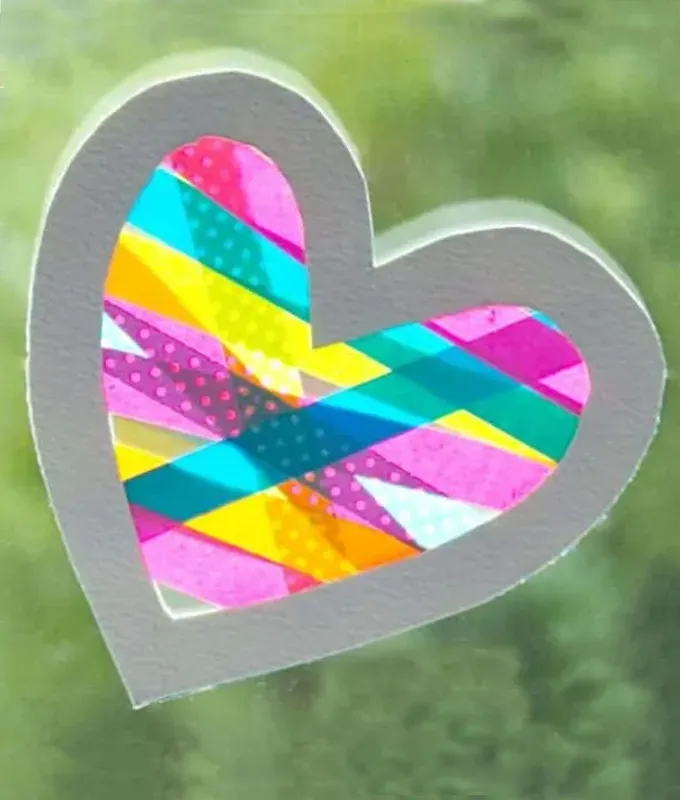 valentines-crafts-for-kids: A washi tape and paper suncatcher project on a window.' title='70 Fun and Easy Valentine’s Day Crafts for Kids