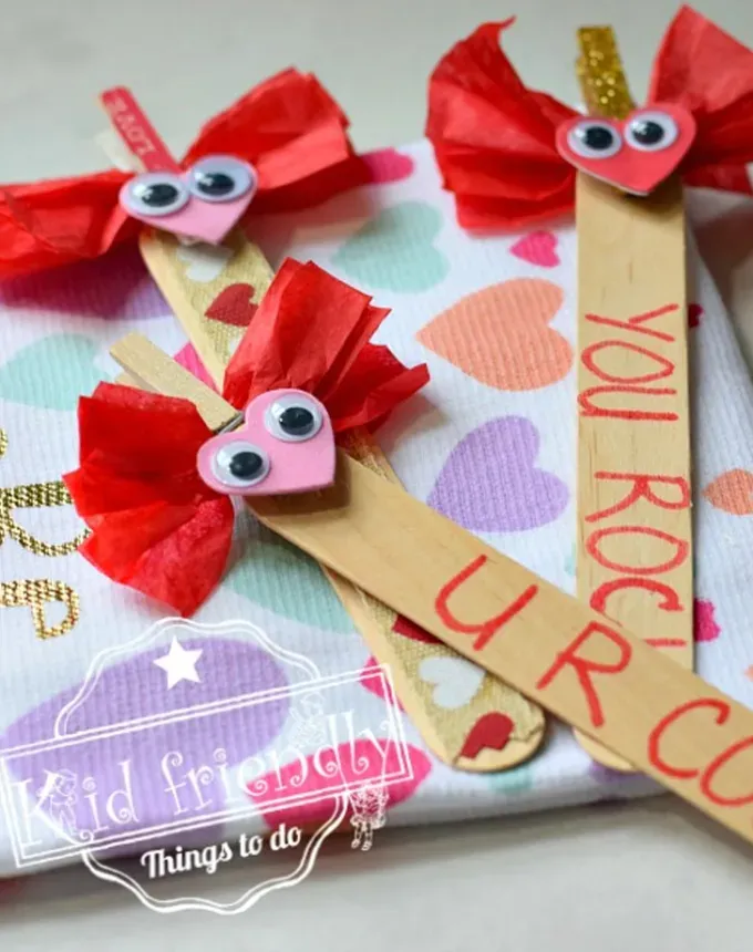 52 Fun and Easy Valentine’s Day Crafts for Kids - Popsicle stick bookmarks with sweet sayings and heart adornments with googly eyes on the top. They are resting on a colorful background covered in pastel hearts.' title='70 Fun and Easy Valentine’s Day Crafts for Kids