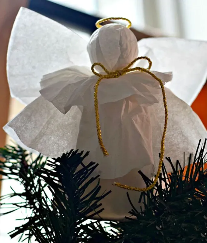 Christmas Crafts for Toddlers - A small angel tree topper made of coffee filters and glittery string sits atop a pine tree.' title='35 Christmas Crafts for Toddlers That They Can Actually Do