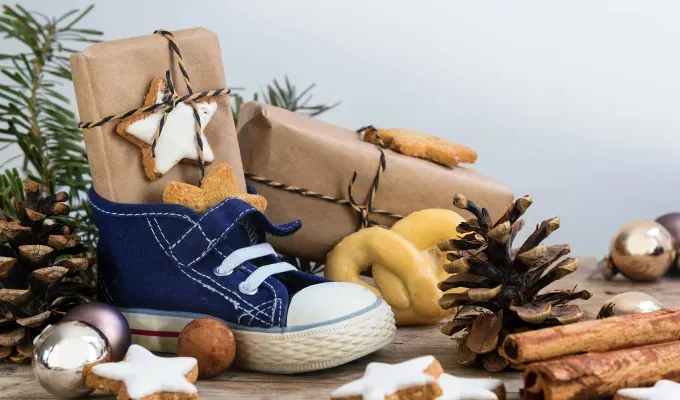french christmas traditions-A smattering of holiday decorations surround a blue pair of shoes with some tied up brown present packages in them.' fetchpriority='auto' title='15 French Christmas Traditions That Are Oh-So Charming