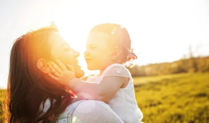 baby-names-that-mean-light: a mother holding a baby girl during sunset.' fetchpriority='auto' title='75 Baby Names That Mean Light