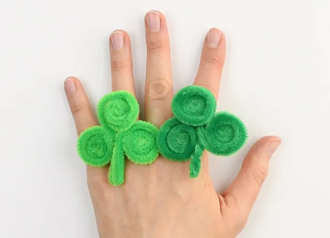st patricks day crafts for kids: two large green shamrock rings on a hand' title='30 Fun and Easy St. Patrick’s Day Crafts for Kids