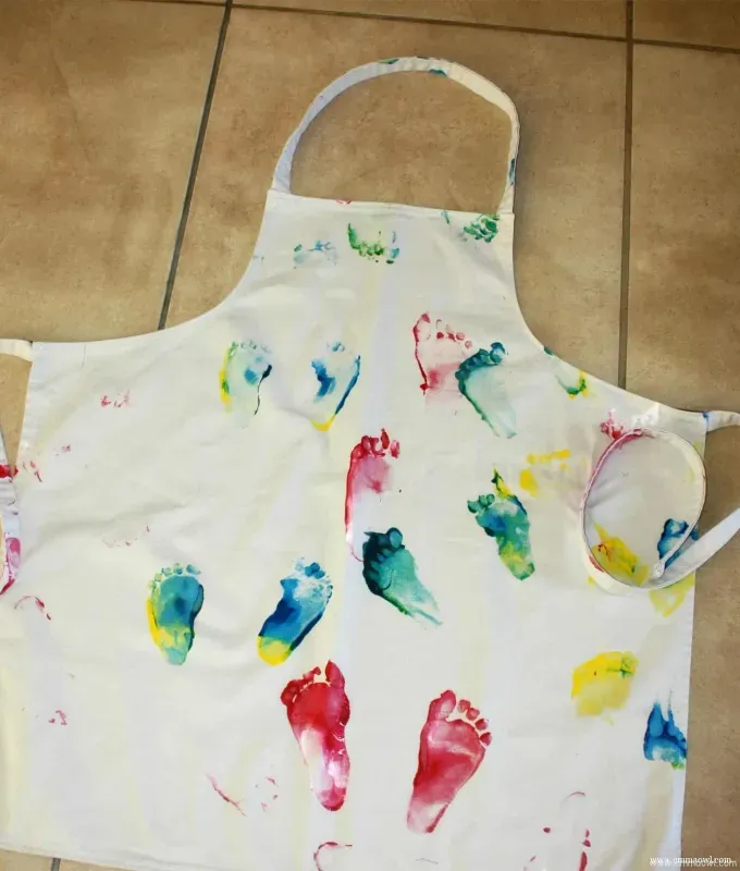 mothers-day-crafts: an apron painted with colorful footprints' title='45 Mother’s Day Crafts for Kids That She’ll Actually Want to Keep