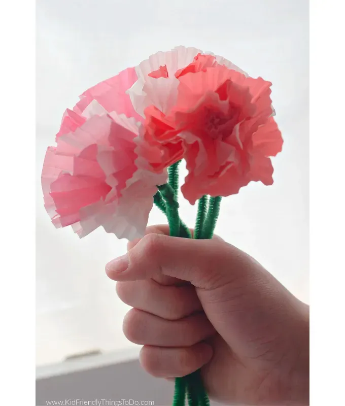 mothers-day-crafts: A person holds a bundle of pink cupcake paper flowers.' title='45 Mother’s Day Crafts for Kids That She’ll Actually Want to Keep