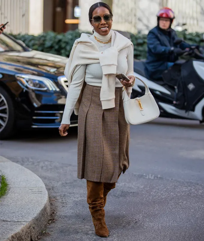 woman wearing a brown pleated midi skirt with brown suede knee high boots' fetchpriority='auto' title='10 Knee-High Boot Outfits That Are Supremely Chic for 2023 (Plus 2 That Are Sadly Outdated)