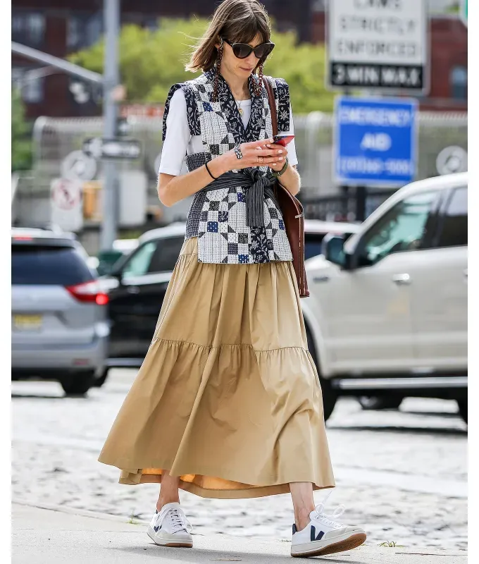 woman wearing a yellow midi skirt and white sneakers' fetchpriority='auto' title='I’m a Fashion Editor—Here Are My 4 Rules for What Shoes to Wear with Skirts