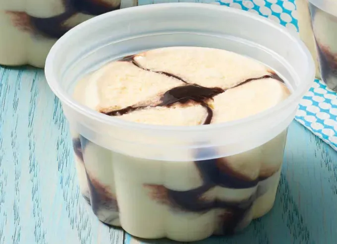 best nostalgic ice cream truck treats: schwan’s vanilla fudge ice cream cup on blue counter' fetchpriority='auto' title='The Best Nostalgic Ice Cream Truck Treats of All Time Ranked