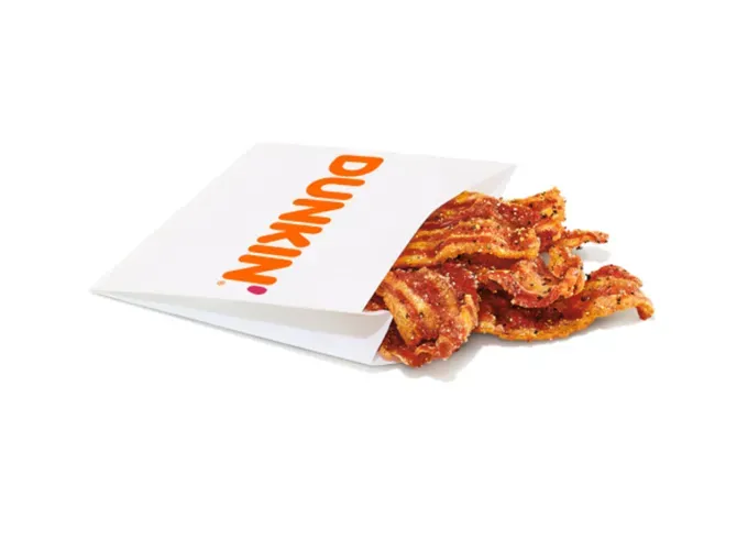 Keto at Dunkin Donuts - A white paper sleeve full of bacon strips from Dunkin on a white background.' title='How to Eat Keto at Dunkin’ Donuts: 15 Low-Carb Foods and Drinks We Love