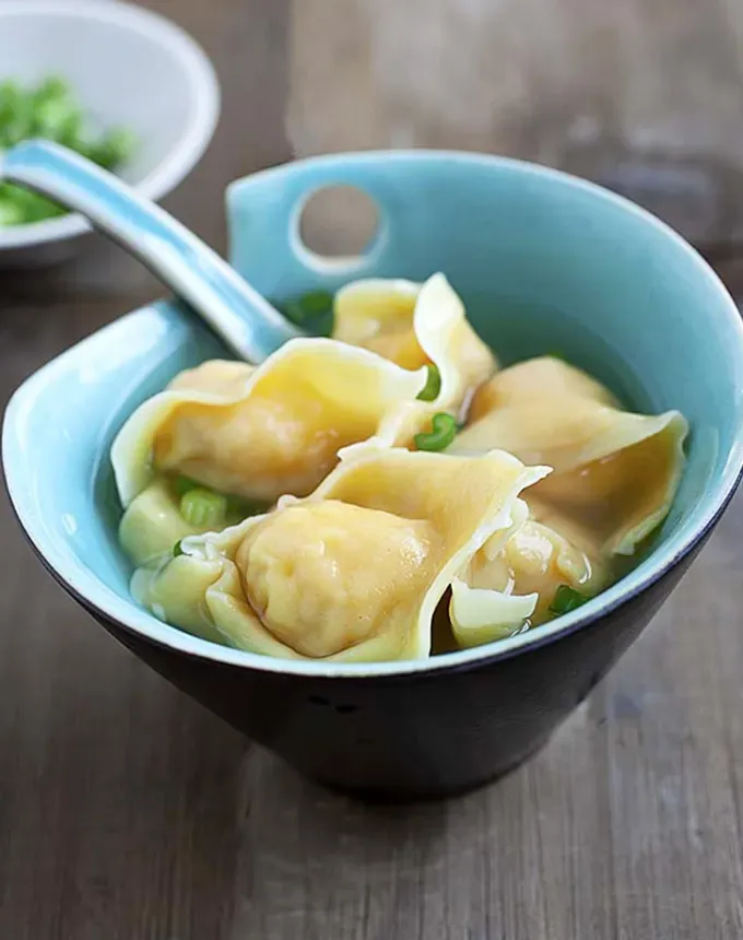 traditional chinese foods: wonton soup in a blue bowl with sliced scallions' title='20 Traditional Chinese Food Dishes You Need to Try According to a Chinese-Malaysian Chef
