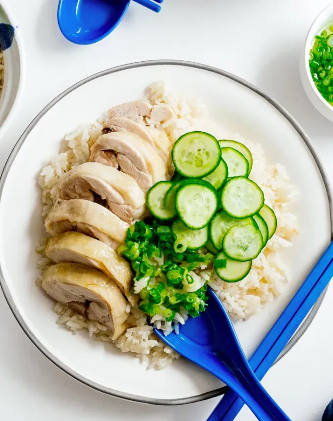 traditional chinese foods: hainanese chicken rice with cucumbers on a plate' title='20 Traditional Chinese Food Dishes You Need to Try According to a Chinese-Malaysian Chef