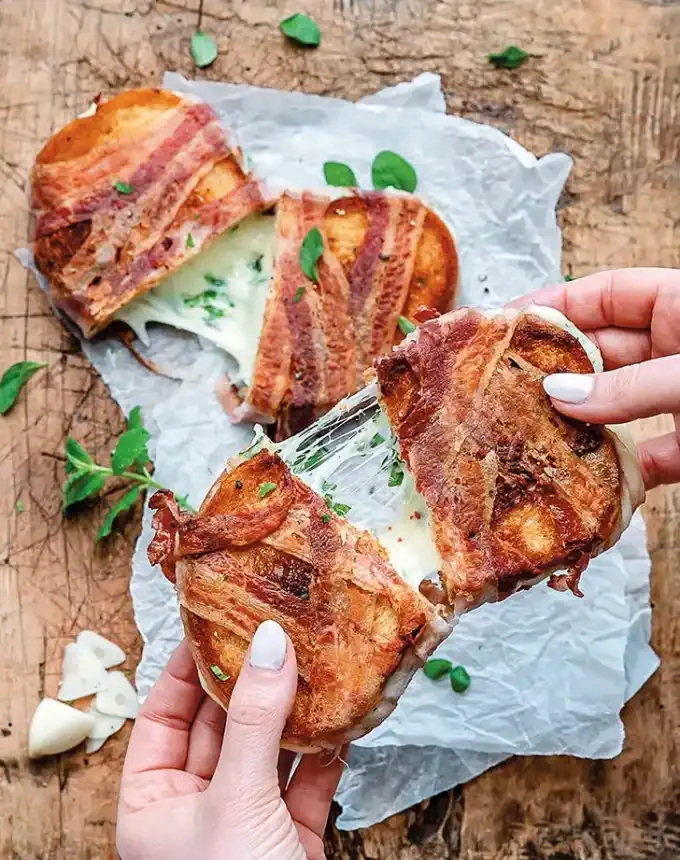 easy lunch ideas: two pancetta-wrapped grilled cheese sandwiches one on a piece of parchment and the other being pulled apart by two hands' title='82 Easy Lunch Ideas That Are Fast Low-Fuss and Foolproof