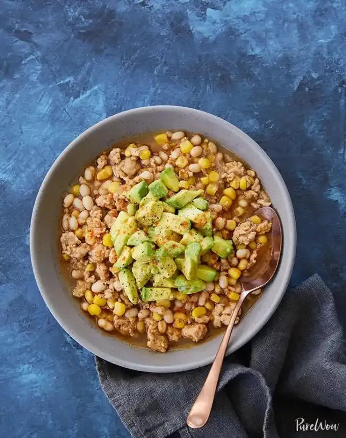 easy lunch ideas: aerial of white turkey chili with avocado in a bowl with a spoon' title='82 Easy Lunch Ideas That Are Fast Low-Fuss and Foolproof
