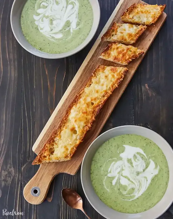 easy lunch ideas: aerial of asiago-crusted baguette on cutting board between two bowls of 15-minute cucumber-avocado blender soup' title='82 Easy Lunch Ideas That Are Fast Low-Fuss and Foolproof