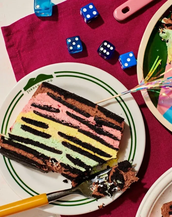easy summer dessert recipes: slice of rainbow cookie icebox cake on a plate surrounded by dice and a red linen' title='92 Easy Summer Desserts to Devour from Now Until Labor Day