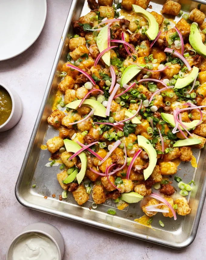 easy dinner recipes: sheet tray of tater tots topped with melted cheese avocado onions and cilantro' title='65 Easy Dinner Recipes for Beginners (That Even the Most Culinarily Challenged Can Manage)