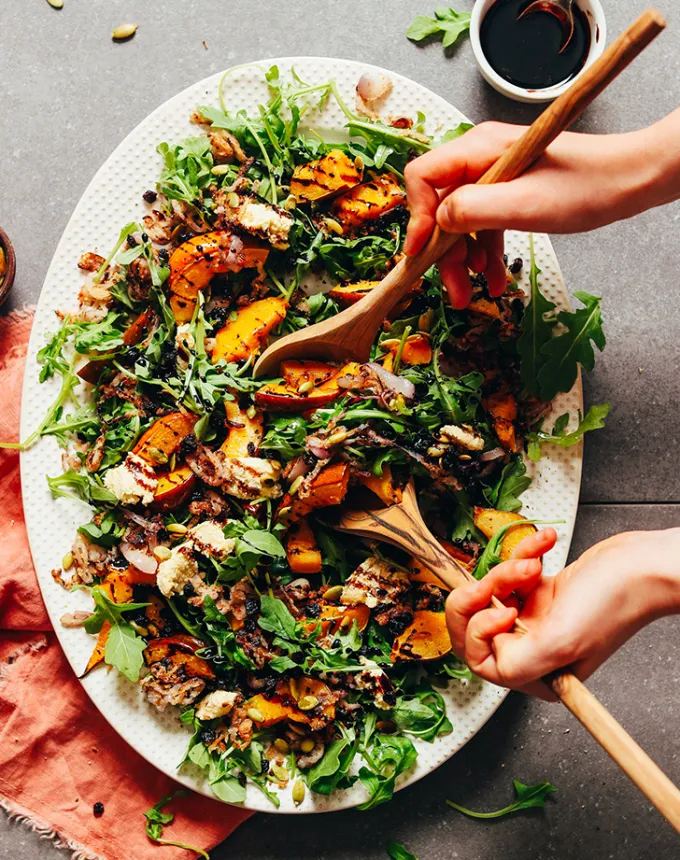 best big-batch recipes: person using salad tongs to scoop roasted squash salad with shallots and balsamic reduction' title='76 Big-Batch Dishes & Recipes to Feed a Crowd