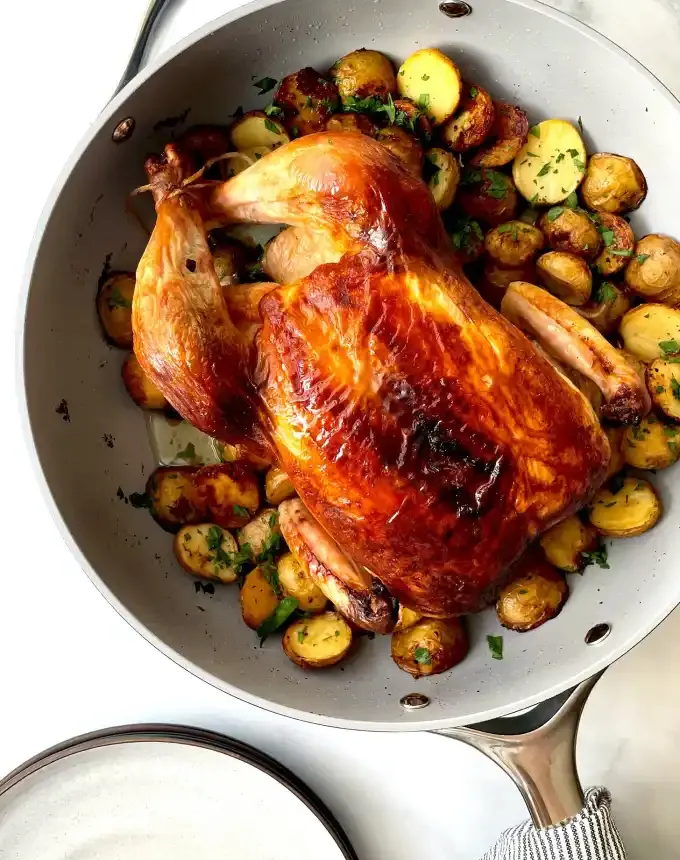 best big-batch recipes: whole roast chicken in a skillet next to potatoes cooked in chicken fat' title='76 Big-Batch Dishes & Recipes to Feed a Crowd