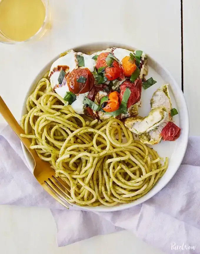 best big-batch recipes: baked caprese chicken on a plate with pesto noodles' title='76 Big-Batch Dishes & Recipes to Feed a Crowd