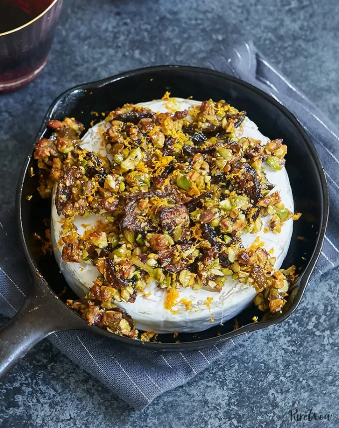 best big-batch recipes: baked brie topped with figs pistachios and orange zest in a small cast iron skillet' title='76 Big-Batch Dishes & Recipes to Feed a Crowd