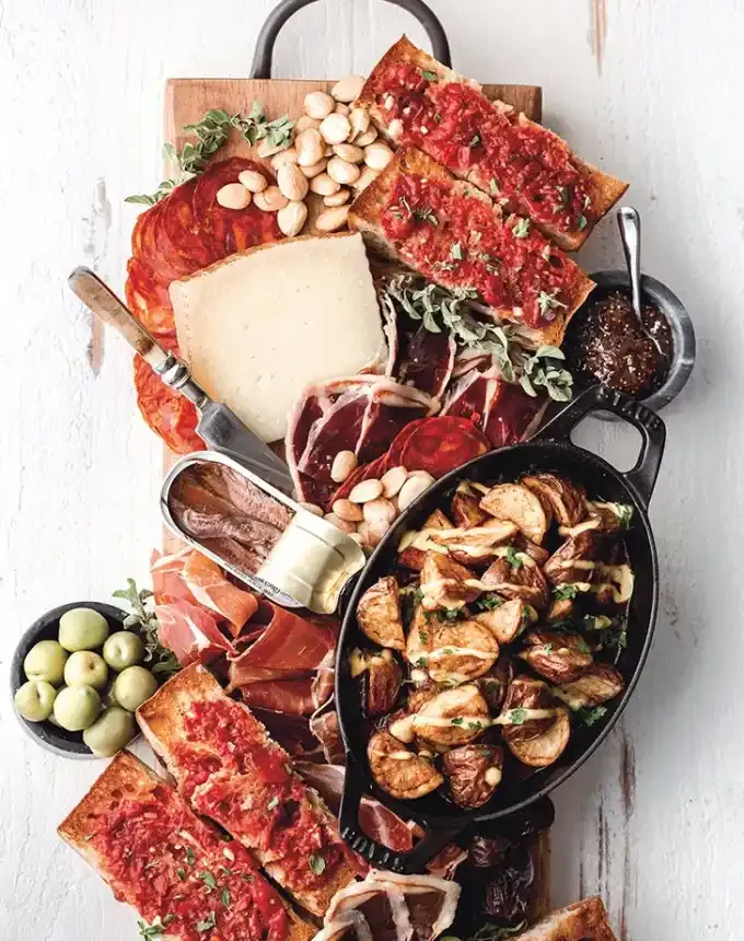 best big-batch recipes: spanish-inspired tapas board with manchego chorizo olives nuts patatas bravas pan con tomate and meats' title='76 Big-Batch Dishes & Recipes to Feed a Crowd
