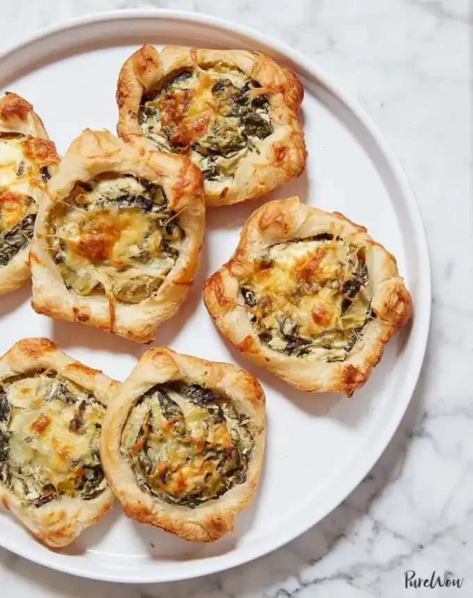 best big-batch recipes: six spinach-artichoke puff pastry squares on a white plate' title='76 Big-Batch Dishes & Recipes to Feed a Crowd