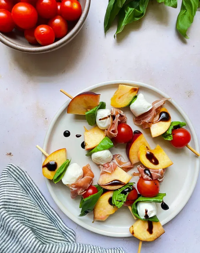 finger food recipes for a crowd: a plate of tomato peach caprese skewers' title='68 Easy Finger Food Appetizers Everyone Will Love