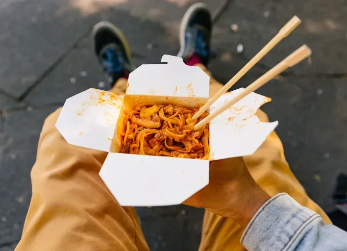 chow mein vs lo mein: first-person perspective of a person holding a takeout box of noodles with chopsticks' fetchpriority='auto' title='Chow Mein vs. Lo Mein: What’s the Difference Between These Noodle Dishes?