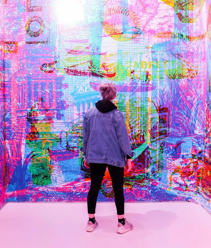 things-to-do-on-a-sunday-in-nyc: a person standing in front of a color splattered wall.' title='18 Things to Do on a Sunday in NYC That Are Anything But Boring