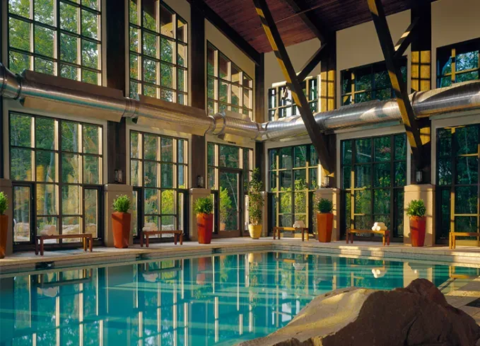 Cozy Winter Weekend Getaways from New York - An indoor pool at sunset light streaming through the dozens of windows that make up the walls.' title='The 34 Coziest Winter Weekend Getaways from NYC in 2025