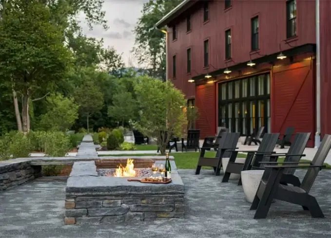 Cozy Winter Weekend Getaways from New York - A fire-pit with some gray wood Adirondack chairs is positioned outside of a red wooden building at The Williams.' title='The 34 Coziest Winter Weekend Getaways from NYC in 2025