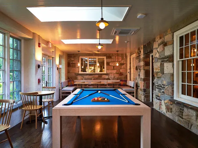 Cozy Winter Weekend Getaways from New York - A pool table is centered in a brick lined sun room at the Troutbeck.' title='The 34 Coziest Winter Weekend Getaways from NYC in 2025