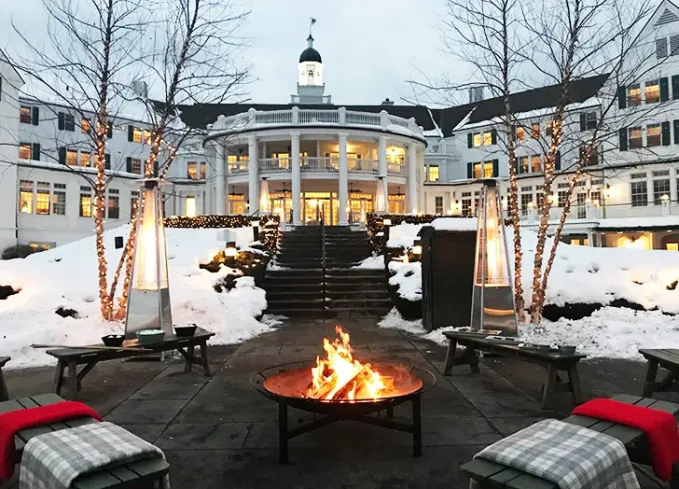 Cozy Winter Weekend Getaways from New York - A cozy fire-pit sits in front of The Sagamore Resort in the winter.' title='The 34 Coziest Winter Weekend Getaways from NYC in 2025