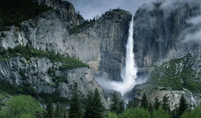 father-son-trip-ideas: A photo of a large waterfall at Yosemite state park in California. There are lots of trees surrounding the waterfall and rocky mountain surfaces.' title='10 Father-Son Trip Ideas for Some Serious Bonding