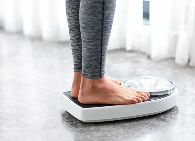 woman weighing herself' fetchpriority='auto' title='8 Things That Might Happen If You Stop Drinking Soda