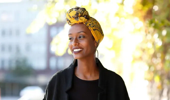 What Might Happen If You Stop Drinking Soda - A young woman with a yellow hair wrap and hoop earrings smiles at something off camera.' fetchpriority='auto' title='8 Things That Might Happen If You Stop Drinking Soda