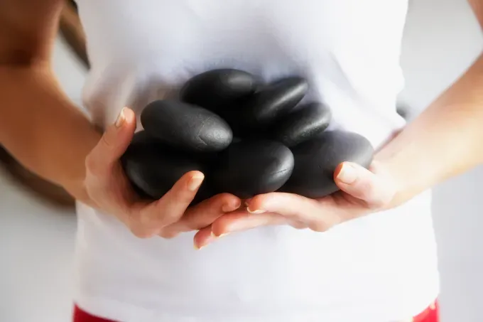 hot stone massage woman holding hot stones' fetchpriority='auto' title='6 Hot Stone Massage Benefits and Risks Explained by an Expert